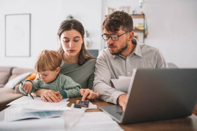 photo - Family of Three with a Toddler Working on Home Budget Paying Bills in Living Room