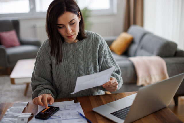 photo - Woman Using a Calculator and Checking her Statement at Home